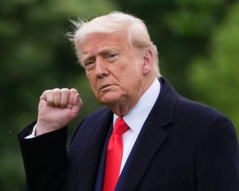 President Donald Trump raises a fist while wearing a red tie, amid reports Wall Street now calls him “TACO” for backing down on tariffs