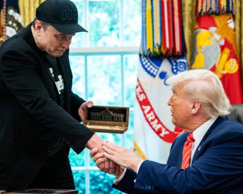 Donald Trump hands a ceremonial box to Elon Musk during a White House event