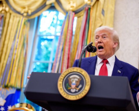 Donald Trump speaks animatedly at the presidential podium in the Oval Office, appearing mid-sentence during a fiery address