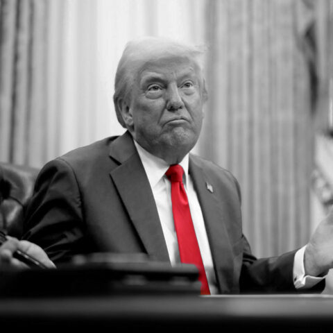 Donald Trump at the Resolute Desk with a confused expression, in black and white except for his red tie