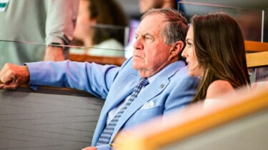 Bill Belichick and Jordon Hudson seated together, speaking privately