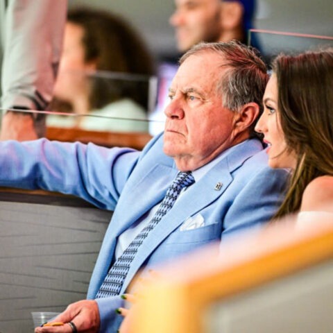 Bill Belichick and Jordon Hudson seated together, speaking privately