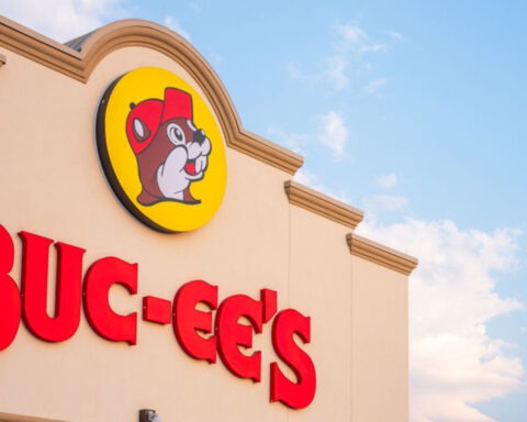 Buc-ee’s store sign with beaver logo on building exterior against a blue sky.