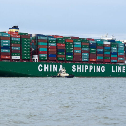 Massive China Shipping Line cargo ship entering U.S. port with hundreds of containers stacked on board
