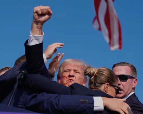 Donald Trump being escorted away after assassination attempt, blood on face