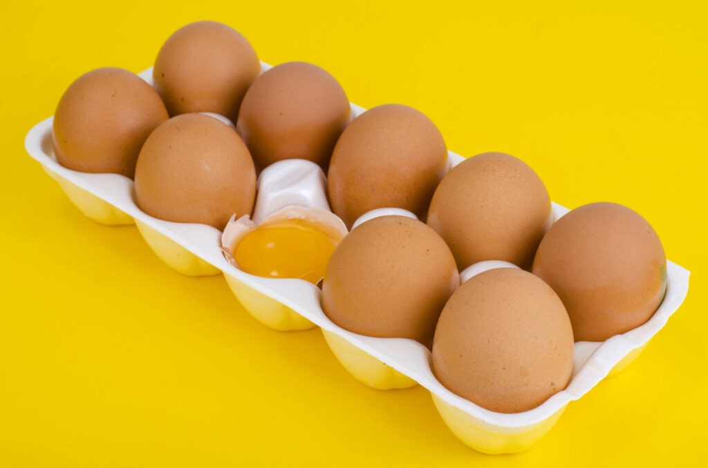 brown eggs with one egg cracked open in the center