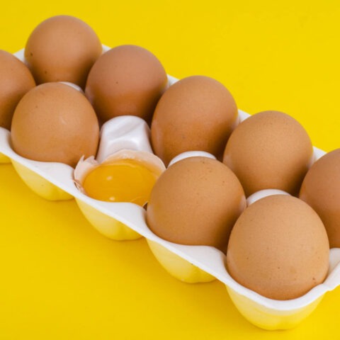 brown eggs with one egg cracked open in the center