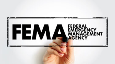 Hand underlining the FEMA logo, which stands for Federal Emergency Management Agency