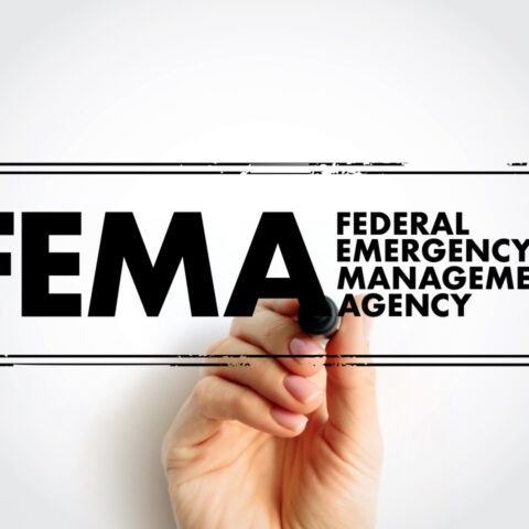 Hand underlining the FEMA logo, which stands for Federal Emergency Management Agency