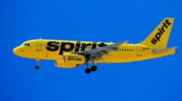 Spirit Airlines yellow airplane in flight under blue sky