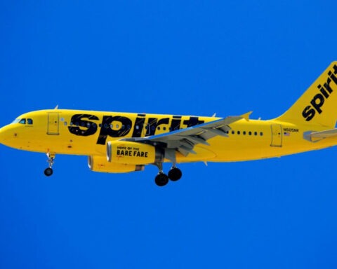Spirit Airlines yellow airplane in flight under blue sky