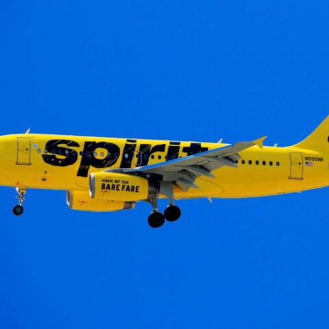 Spirit Airlines yellow airplane in flight under blue sky