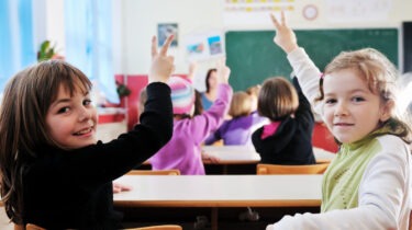 Teacher with textbook in front of confused students in classroom