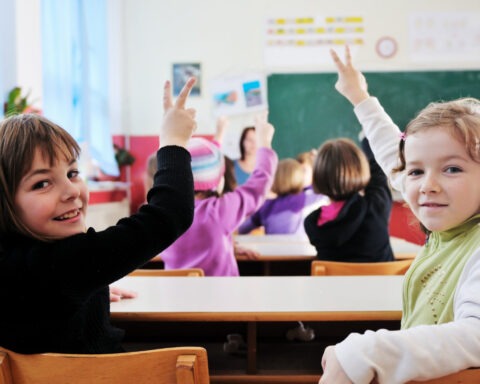 Teacher with textbook in front of confused students in classroom