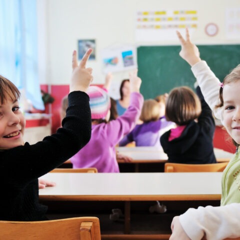 Teacher with textbook in front of confused students in classroom