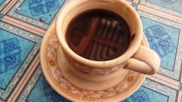 Cup of coffee isolated on blue checkered tablecloth background. Cup of coffee