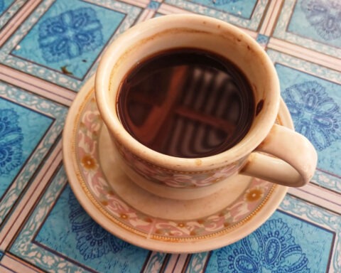 Cup of coffee isolated on blue checkered tablecloth background. Cup of coffee