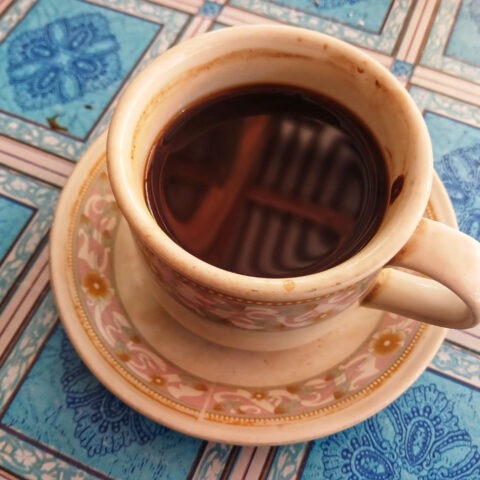 Cup of coffee isolated on blue checkered tablecloth background. Cup of coffee