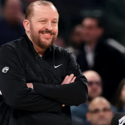 New York Knicks coach Tom Thibodeau winks while smiling courtside during an NBA game.