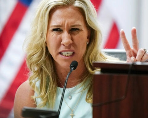 Marjorie Taylor Greene speaking intensely at a congressional hearing, gesturing with fingers raised