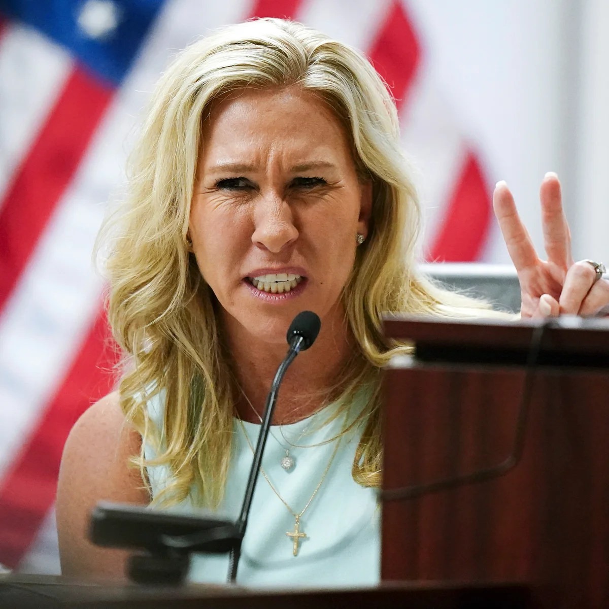 Marjorie Taylor Greene speaking intensely at a congressional hearing, gesturing with fingers raised