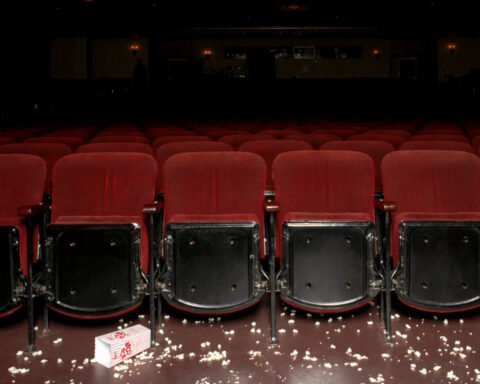 Empty theater seats with scattered popcorn and a tipped popcorn box on the floor, symbolizing a popcorn shortage.