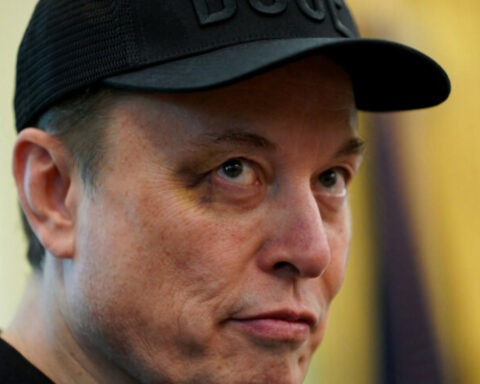 Elon Musk with a visible black eye wearing a black DOGE hat