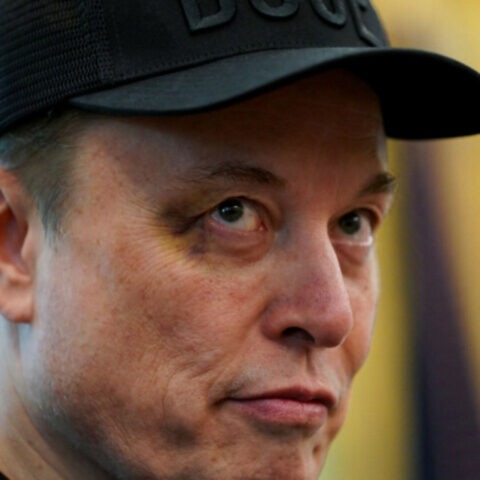 Elon Musk with a visible black eye wearing a black DOGE hat