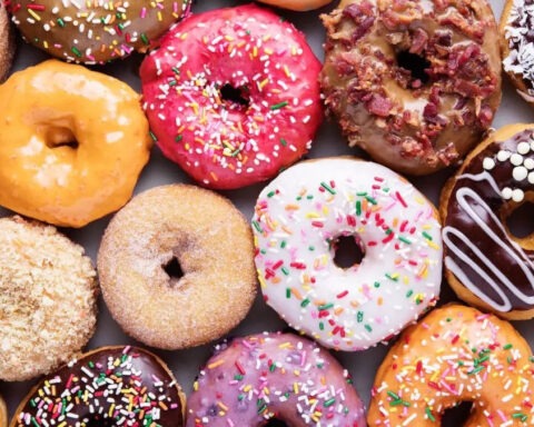 Colorful assorted donuts with frosting, sprinkles, and toppings arranged in a close-up flat lay