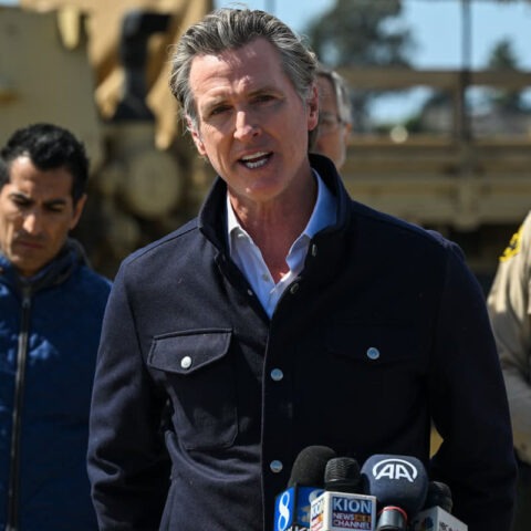 California Governor Gavin Newsom speaks at a press conference flanked by officials and National Guard vehicles during tense standoff with Trump administration