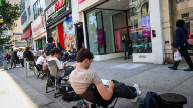 Gamers waiting in a long line outside GameStop and T-Mobile stores in lawn chairs during the Nintendo Switch 2 release.