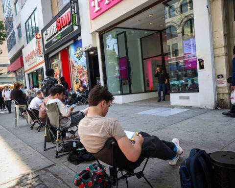 Gamers waiting in a long line outside GameStop and T-Mobile stores in lawn chairs during the Nintendo Switch 2 release.