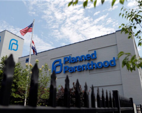 Protesters holding signs in support of Planned Parenthood outside a government building
