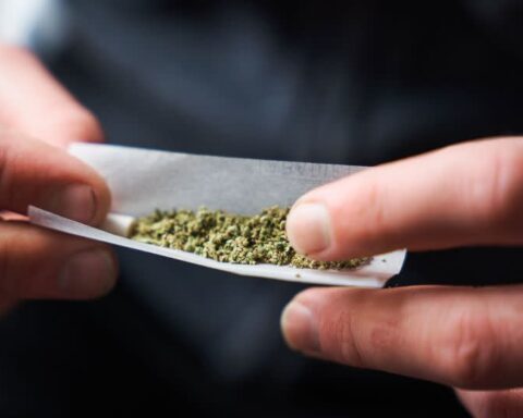 Close-up of a confused man holding a joint while reading health warning