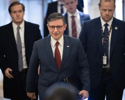 Speaker Mike Johnson walks through Capitol hallway surrounded by aides