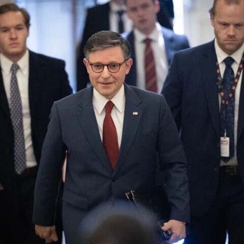 Speaker Mike Johnson walks through Capitol hallway surrounded by aides