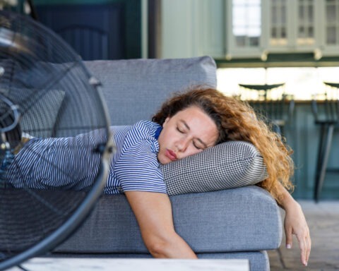 Woman passed out on couch in front of large fan during heatwave