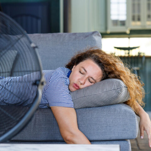 Woman passed out on couch in front of large fan during heatwave