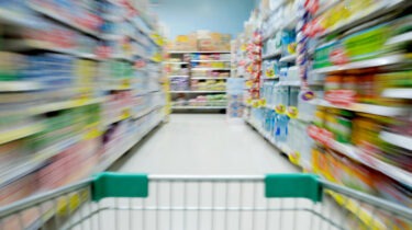 Blurred supermarket aisle seen from shopping cart, symbolizing economic confusion