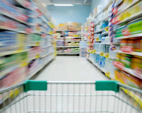 Blurred supermarket aisle seen from shopping cart, symbolizing economic confusion