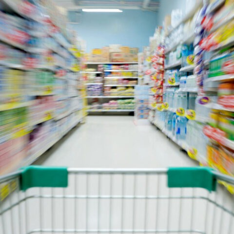 Blurred supermarket aisle seen from shopping cart, symbolizing economic confusion