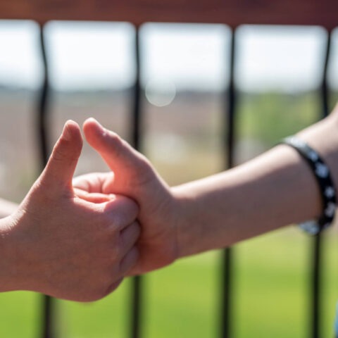 Two people locking thumbs in a game of thumb war outdoors