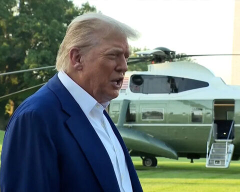 Donald Trump speaking outdoors in front of multiple microphones