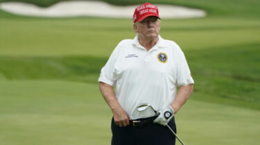 Donald Trump on golf course in red MAGA hat