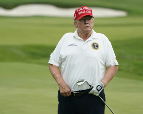 Donald Trump on golf course in red MAGA hat