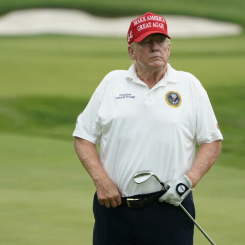Donald Trump on golf course in red MAGA hat