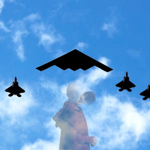 A B2 stealth bomber flies overhead accompanied by fighter jets.