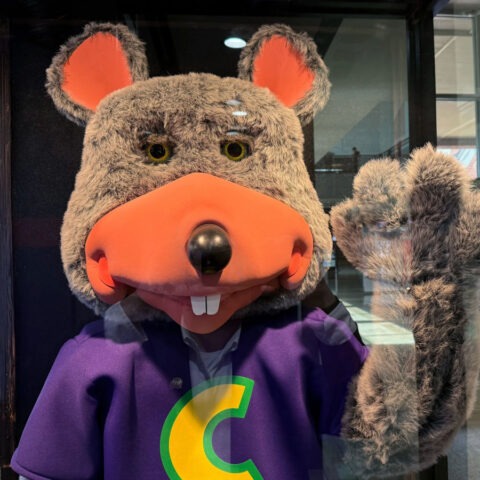 Chuck E. Cheese mascot being arrested by police officer inside restaurant