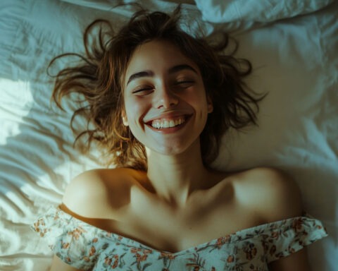 Smiling young woman lying on bed enjoying morning light and comfort