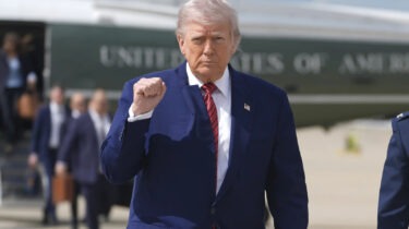 Donald Trump walks away from helicopter with fist raised and wind-blown hair